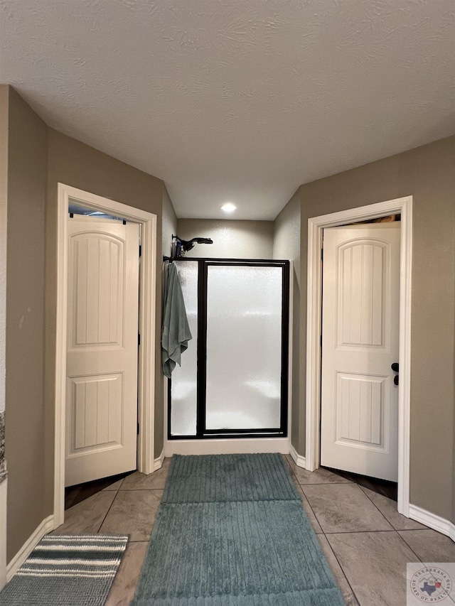 bathroom featuring a textured ceiling, tile patterned floors, and a shower with door