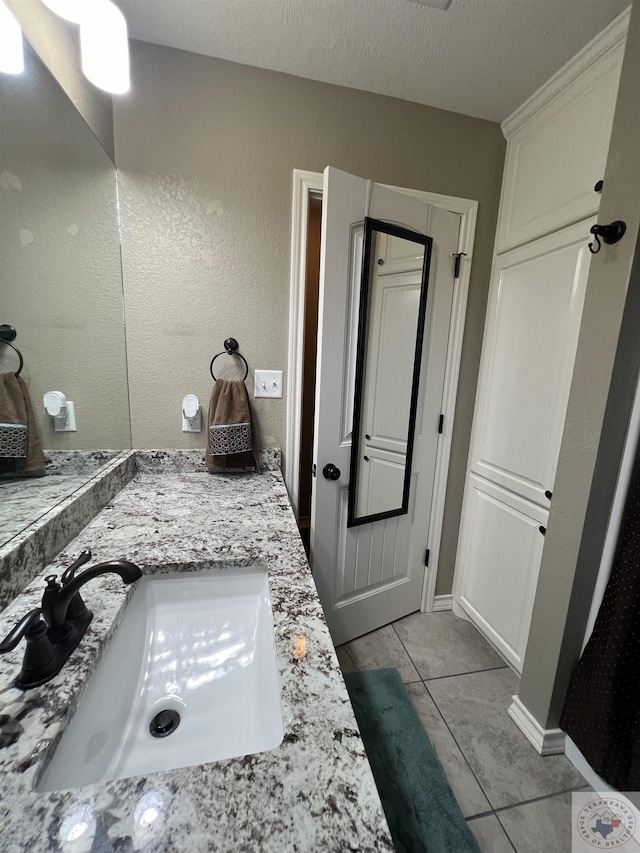 bathroom with a textured ceiling, tile patterned floors, and vanity