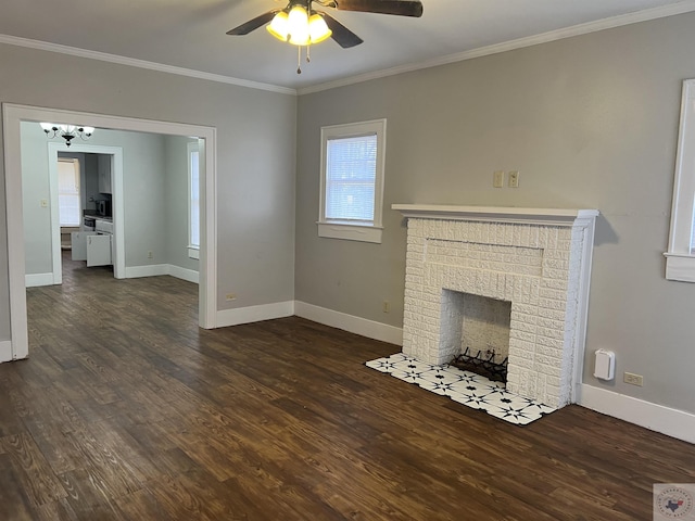 unfurnished living room featuring ornamental molding, dark hardwood / wood-style flooring, ceiling fan with notable chandelier, and a brick fireplace