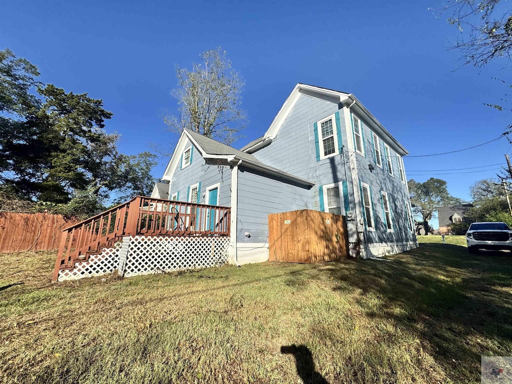 view of property exterior with a wooden deck and a yard