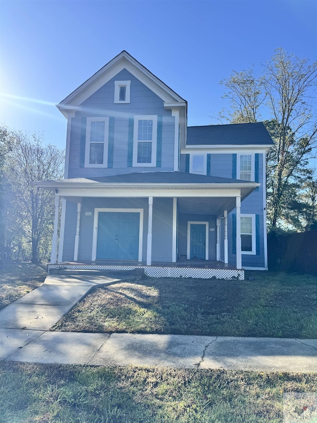 view of front facade featuring covered porch, a front yard, and a garage