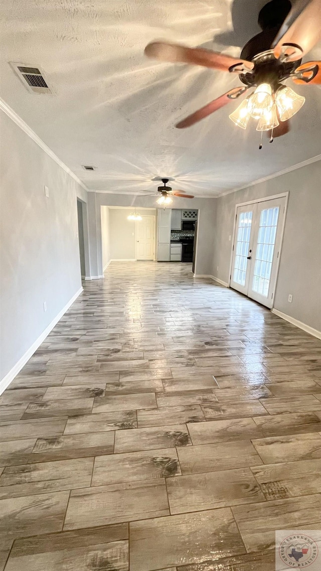 unfurnished living room with ceiling fan, a textured ceiling, ornamental molding, and french doors