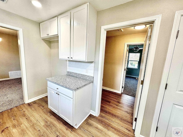 kitchen with backsplash, light hardwood / wood-style floors, and white cabinets