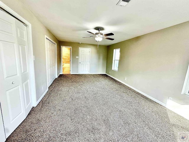 unfurnished bedroom with two closets and ceiling fan