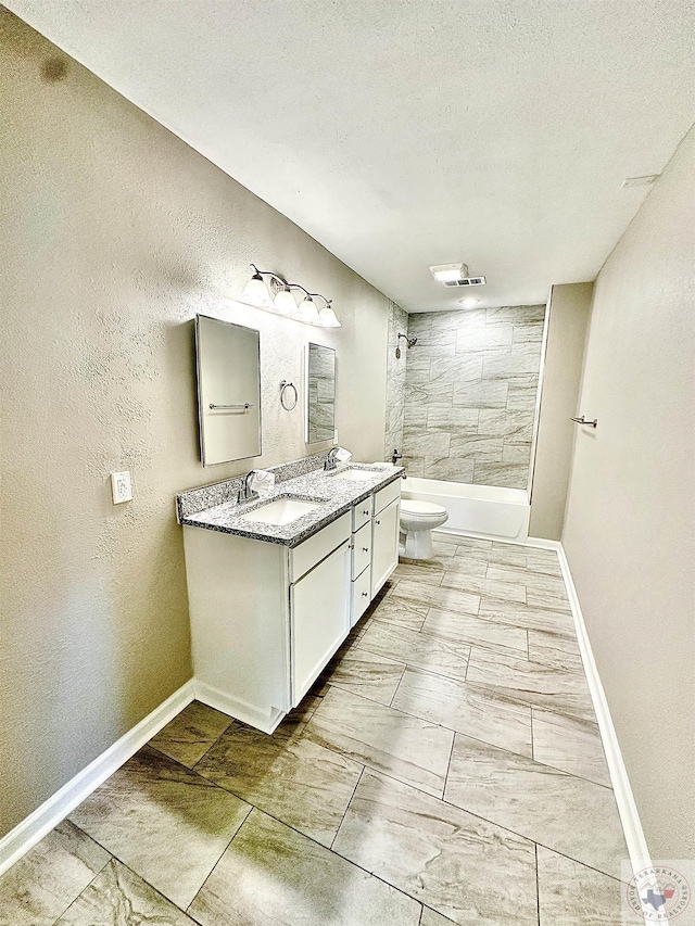 full bathroom featuring tiled shower / bath combo, vanity, a textured ceiling, and toilet