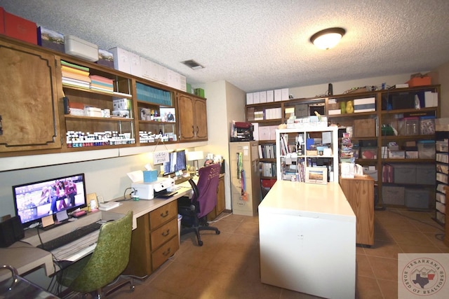 tiled home office with a textured ceiling and built in desk