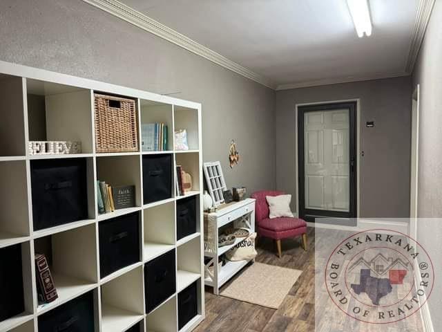 sitting room with crown molding and wood-type flooring