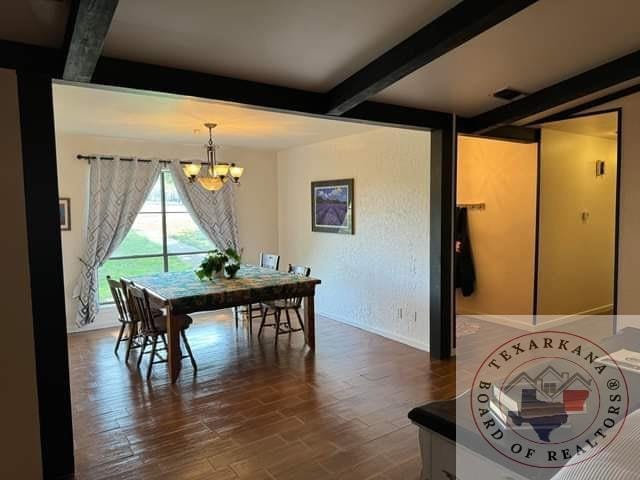 dining space with dark hardwood / wood-style floors, beam ceiling, and a notable chandelier