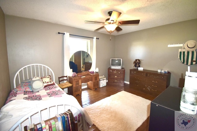 bedroom with ceiling fan, a textured ceiling, and dark hardwood / wood-style flooring