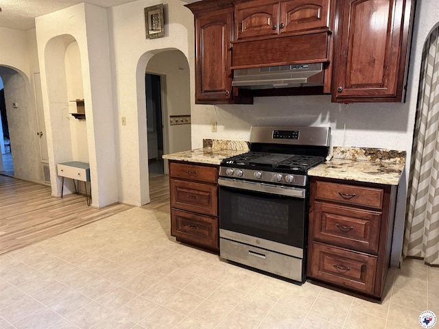 620 E 27th St, Texarkana, AR 71854 - kitchen featuring gas stove, under cabinet range hood, arched walkways, and light stone counters