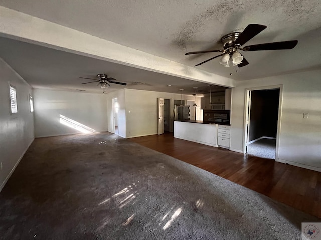 unfurnished living room with a textured ceiling, dark hardwood / wood-style floors, and ceiling fan