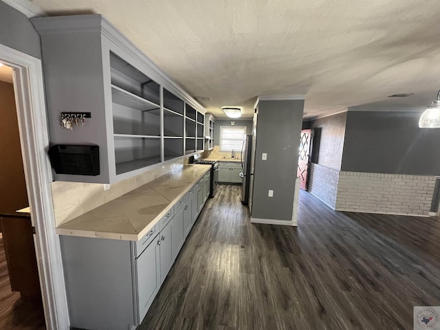 kitchen with dark hardwood / wood-style flooring, stainless steel appliances, a textured ceiling, and brick wall