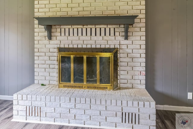 interior details with wood-type flooring, wooden walls, and a fireplace