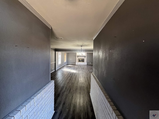 corridor with ornamental molding, dark hardwood / wood-style floors, and a chandelier