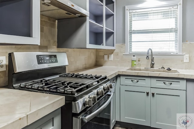 kitchen featuring sink, backsplash, light stone counters, extractor fan, and stainless steel gas range oven