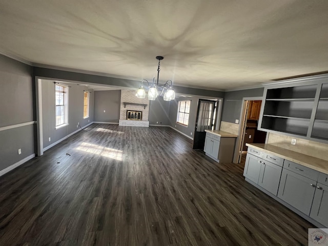 interior space with an inviting chandelier, dark wood-type flooring, a wealth of natural light, and crown molding