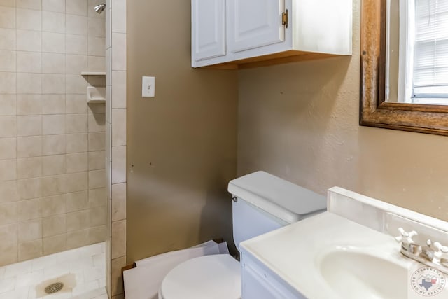 bathroom with tiled shower, vanity, and toilet