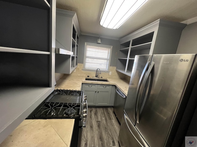 kitchen with sink, ornamental molding, appliances with stainless steel finishes, gray cabinets, and light hardwood / wood-style floors