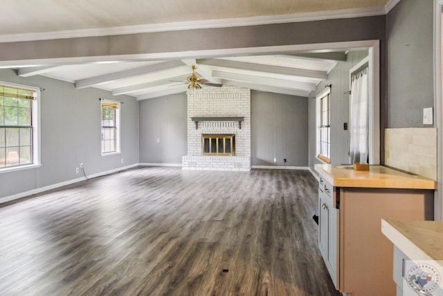 unfurnished living room with a brick fireplace, dark wood-type flooring, vaulted ceiling with beams, and ceiling fan