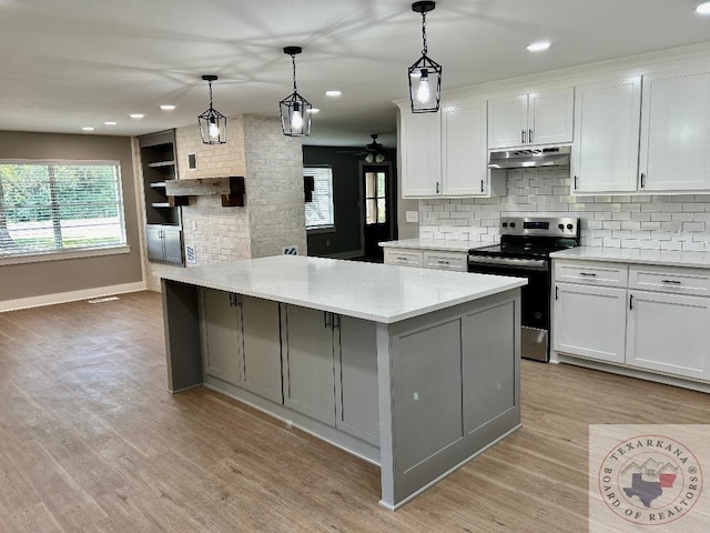 kitchen featuring white cabinets, hanging light fixtures, stainless steel range with electric stovetop, light wood-type flooring, and light stone counters