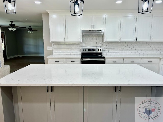 kitchen with light stone counters, white cabinetry, pendant lighting, and electric stove