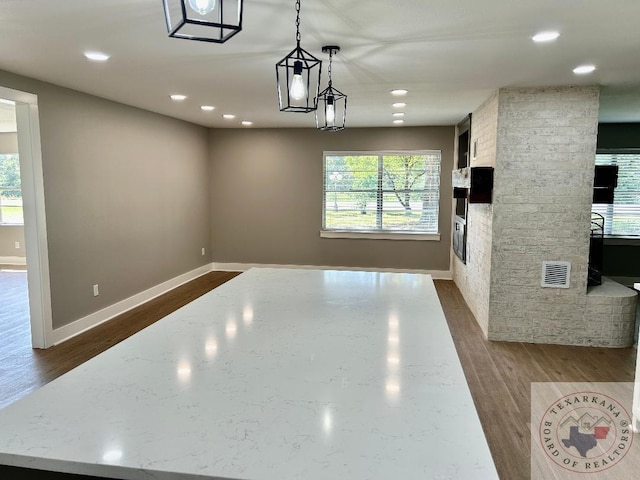 kitchen with light stone counters, pendant lighting, dark hardwood / wood-style flooring, and a fireplace