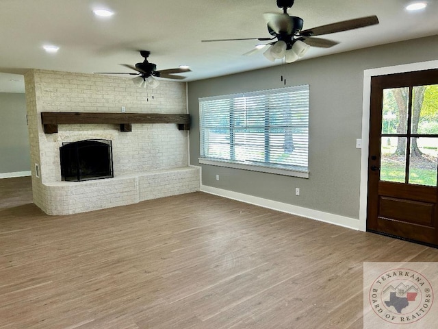 unfurnished living room featuring hardwood / wood-style flooring, ceiling fan, and a fireplace