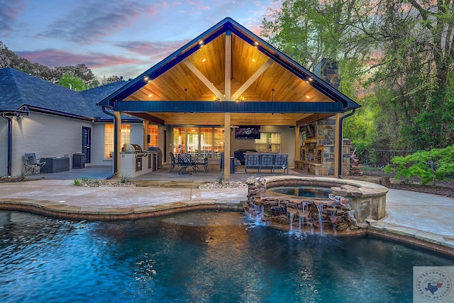 pool at dusk with an in ground hot tub, area for grilling, a patio, and a bar