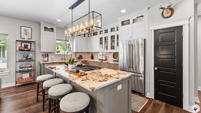 6917 Woodmere Ct, Texarkana, TX 75503 - kitchen with appliances with stainless steel finishes, a breakfast bar, dark wood-style flooring, a kitchen island, and recessed lighting