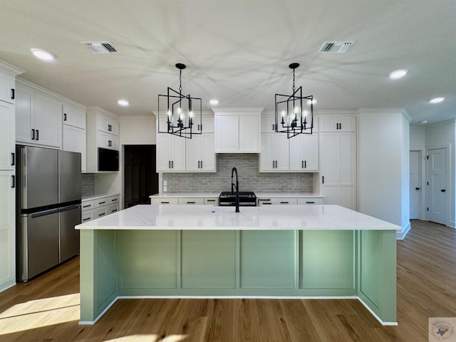 kitchen featuring a spacious island, visible vents, appliances with stainless steel finishes, and wood finished floors