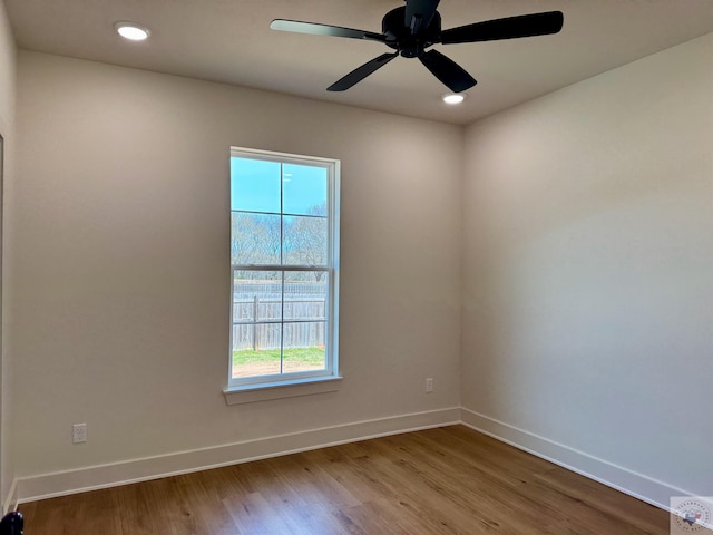 empty room with recessed lighting, plenty of natural light, wood finished floors, and baseboards