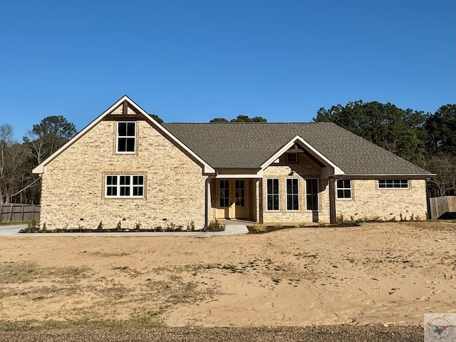 view of front facade with a shingled roof and fence