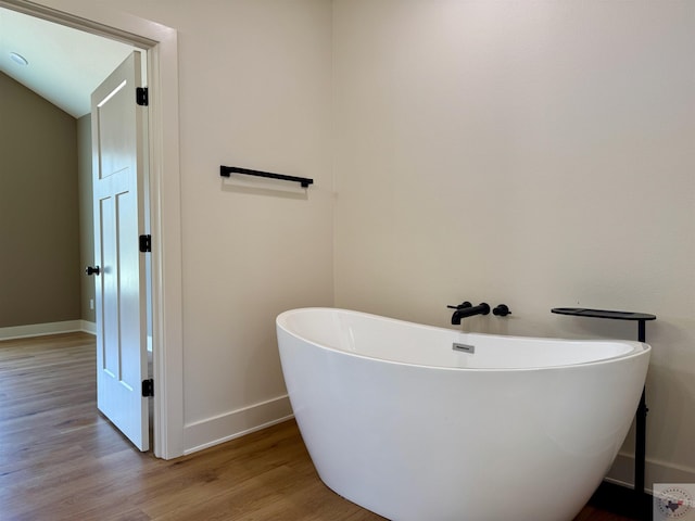 full bath with a soaking tub, baseboards, and wood finished floors