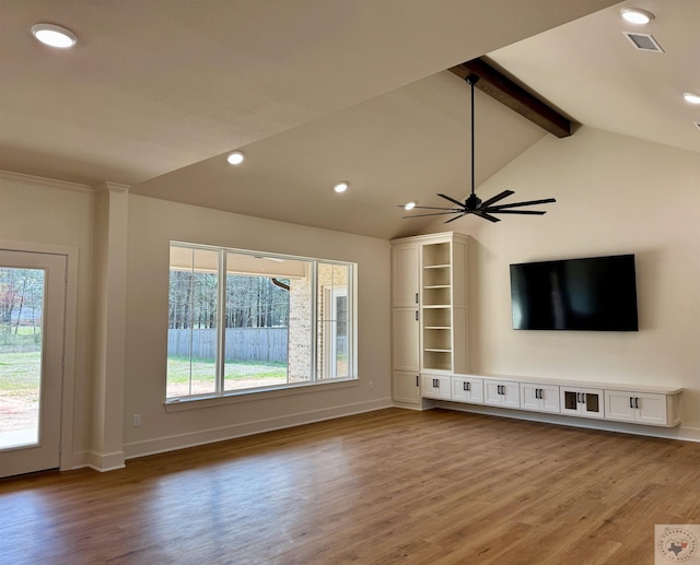 unfurnished living room featuring lofted ceiling with beams, a healthy amount of sunlight, baseboards, and wood finished floors