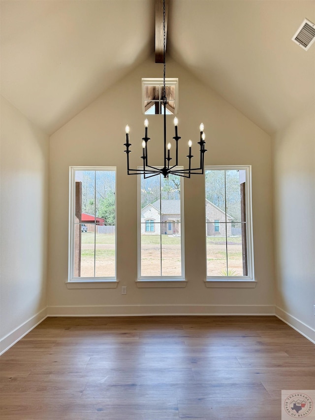 unfurnished dining area with a healthy amount of sunlight, visible vents, lofted ceiling with beams, and wood finished floors