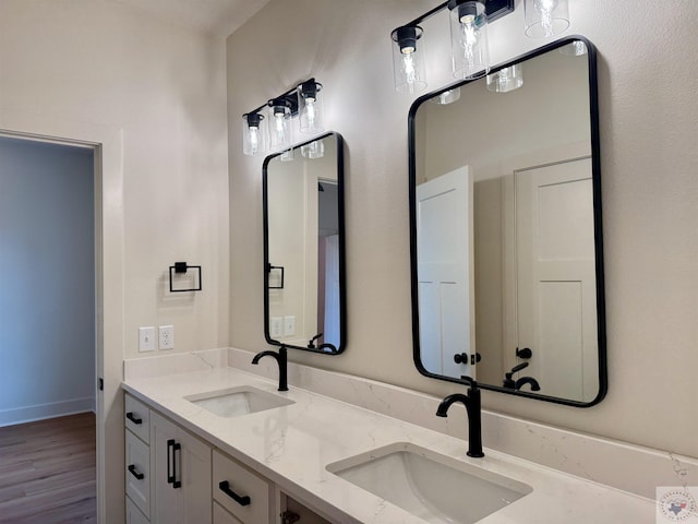 bathroom featuring double vanity, wood finished floors, and a sink