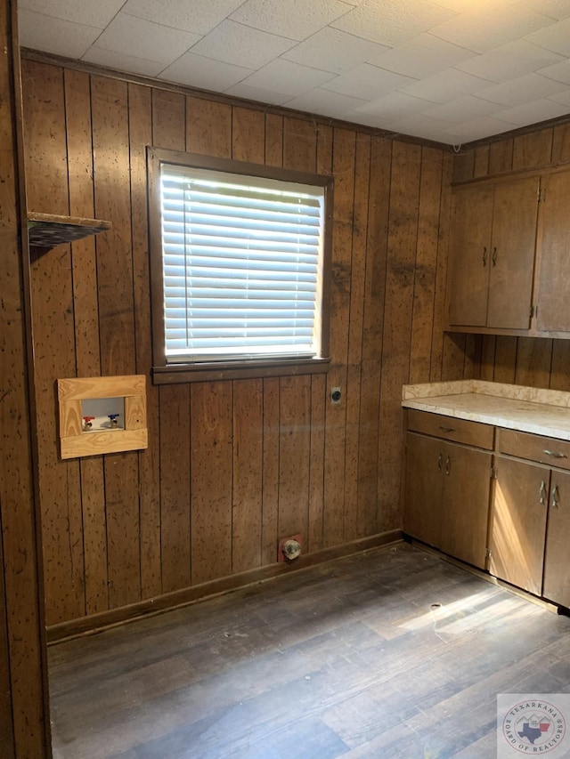 washroom with washer hookup, wood walls, dark hardwood / wood-style floors, and cabinets