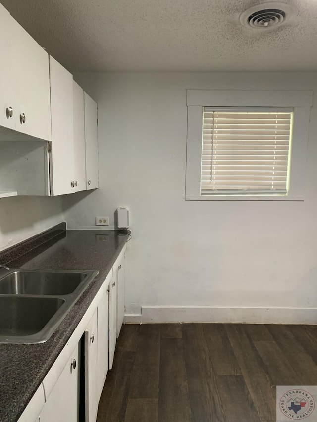 kitchen featuring sink, white cabinetry, dark hardwood / wood-style flooring, and a textured ceiling