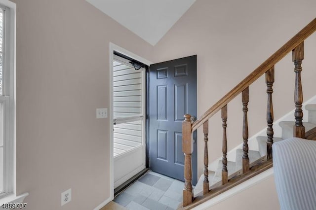 tiled foyer entrance featuring vaulted ceiling