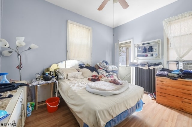 bedroom with radiator heating unit, ceiling fan, and light wood-type flooring