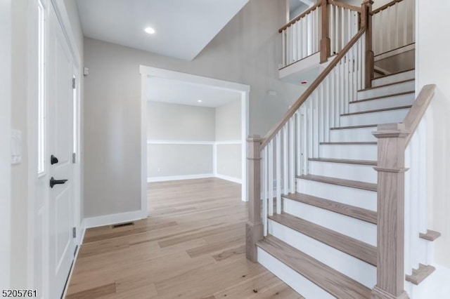 foyer with stairway, visible vents, baseboards, and wood finished floors