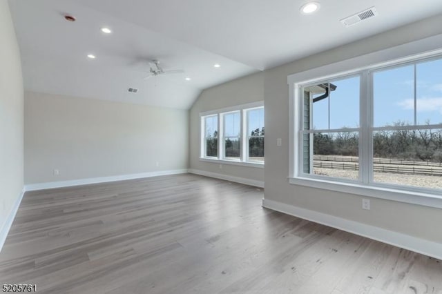 spare room with baseboards, visible vents, lofted ceiling, wood finished floors, and recessed lighting