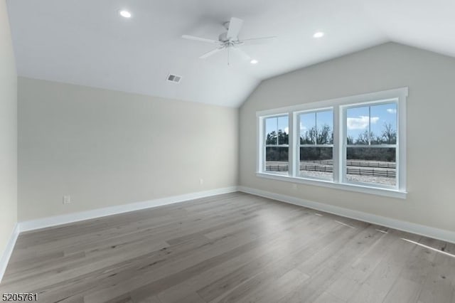 additional living space featuring ceiling fan, wood finished floors, visible vents, baseboards, and vaulted ceiling