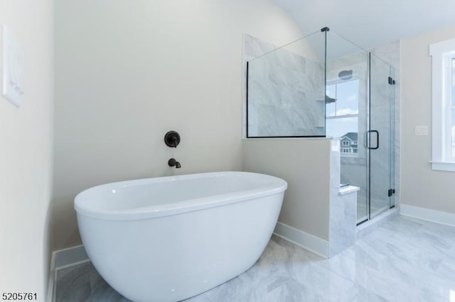 bathroom with a stall shower, a soaking tub, and baseboards