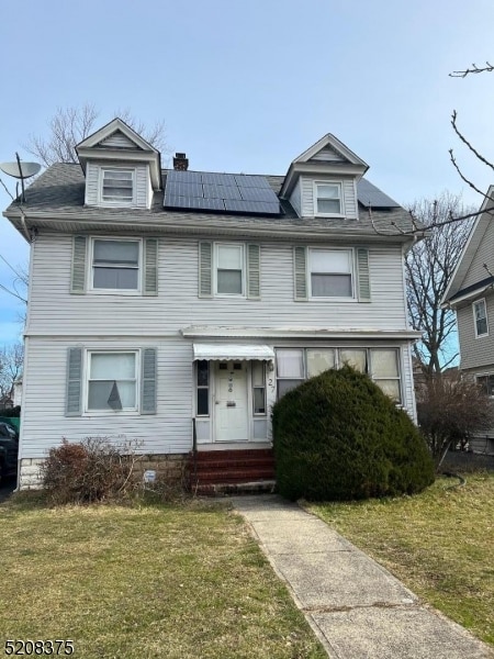 view of front facade featuring a front yard and solar panels