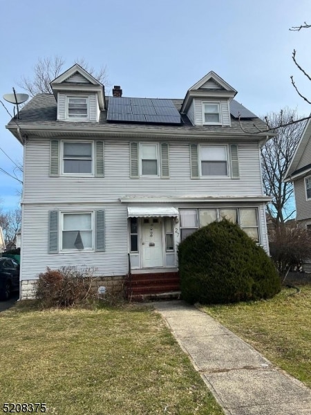 view of front of property featuring a front lawn and solar panels