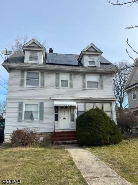 view of front of house featuring a front yard and solar panels