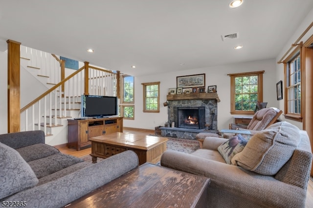 living room featuring light wood-type flooring and a stone fireplace