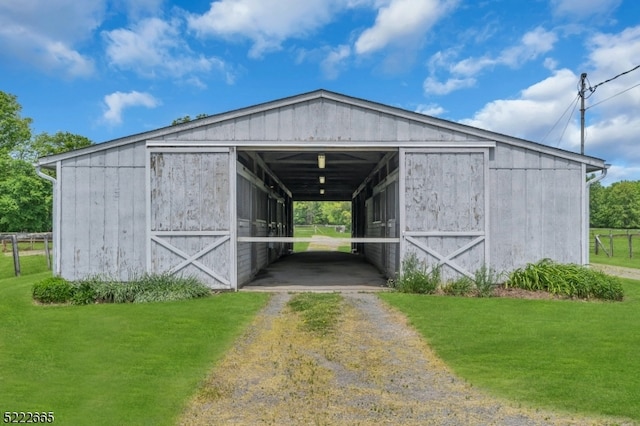 view of horse barn featuring a lawn and an outdoor structure