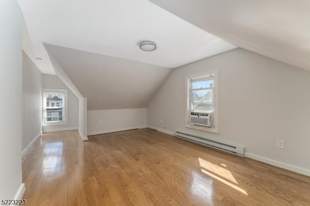 bonus room with lofted ceiling, cooling unit, light wood finished floors, baseboards, and baseboard heating